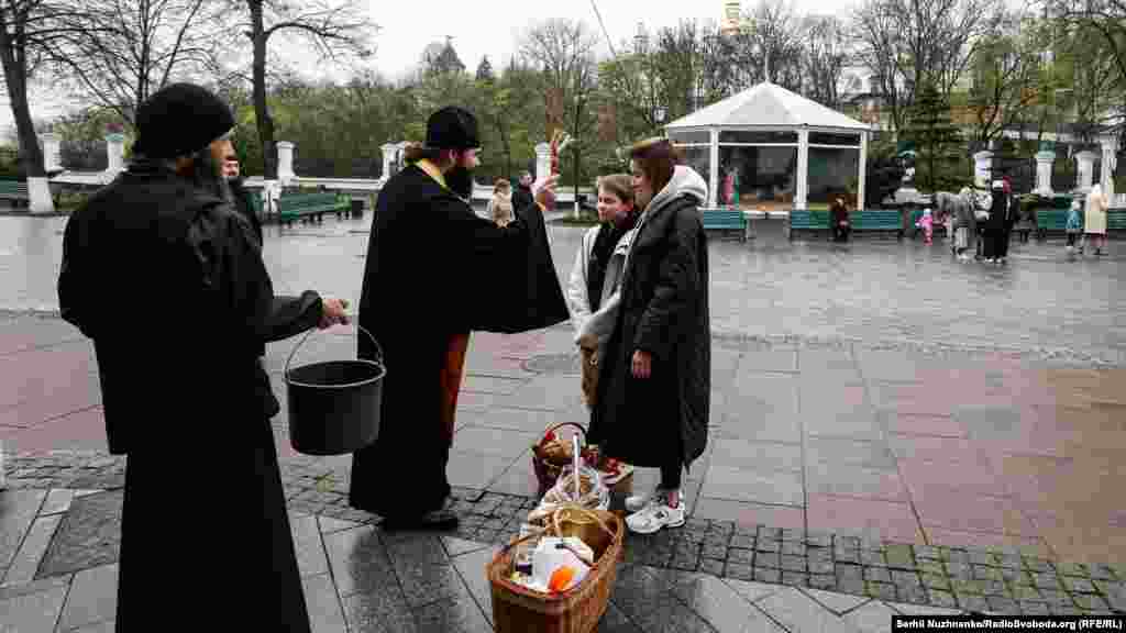 Священник УПЦ (МП) освячують водою вірян на території Нижньої лаври