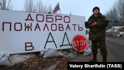 Бойовик російських гібридних сил на блокпосту на в'їзді в Горлівку (Донеччина, Україна). На табличці написано «Ласкаво просимо в пекло». 14 грудня 2014 року