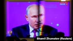 Russian President Vladimir Putin is seen on a screen through a glass door at a press centre during an annual nationwide televised phone-in show in Moscow, Russia June 20, 2019. REUTERS/Shamil Zhumatov - RC14F5EBD700