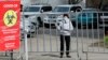 KAZAKHSTAN -- A woman wearing a protective face mask stands behind a fence placed around the residential building quarantined in response to the spread of coronavirus disease (COVID-19) in Almaty, March 24, 2020