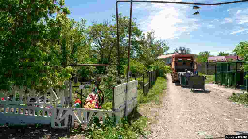 Робочі сміттєвоза біля паркану сільського кладовища