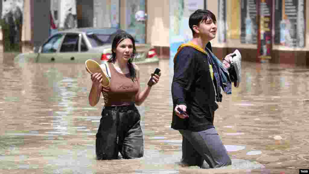 Вода піднялася вище коліна. Сміливці, які ризикнули перейти вулицю, пересуваються босоніж