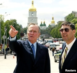 Колишній президент США Джордж Буш (ліворуч) під час приватної поїздки до України у центрі української столиці разом із тодішнім послом в Україні Джоном Едвардом Гербстом. Київ, 21 травня 2004 року