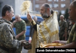 Священник Московського патріархату благословляє Ігоря Гіркіна, який на той час був одним із ватажків угруповання «ДНР», що визнане в Україні терористичним. Окупований Донецьк, 10 липня 2014 року