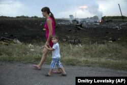 Жінка з дитиною проходить повз одне з місць падіння уламків «Боїнга», збитого російською установкою «Бук», в результаті чого загинуло 298 людей, в тому числі 80 дітей. Донеччина, неподалік села Грабове, 17 липня 2014 року